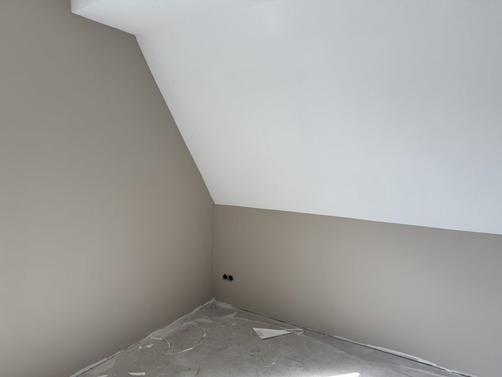 Zolderkamer in een nieuwbouwwoning met een schuine wand en een wit plafond